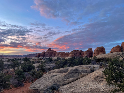 Some of the more robust 'Needles to be' under early morning light. Sunrise may be seen hitting the clouds above, turning them into a nice salmon color. The white sedimentary layer of nearby rock may be seen up close as the dominant layer.