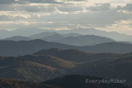 Near sunset under cloudy skies reveals many layers of mountains coming through the haze.